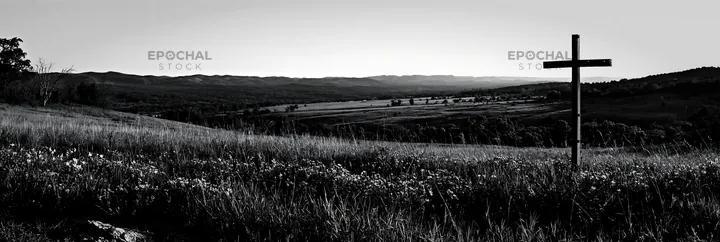 Iron Christian cross overlooking valley meadow - AI-generated stock image