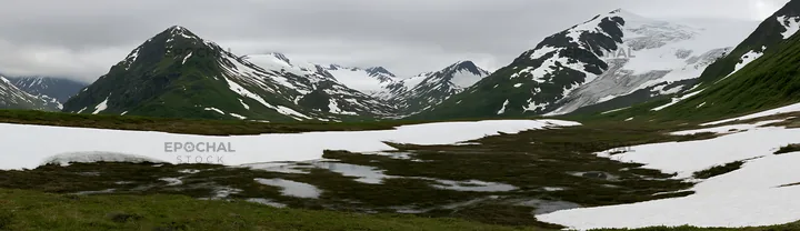 Snowmelt meadow in mountainous landscape with patches of snow - AI-generated stock image