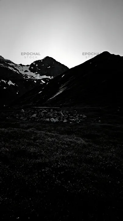 Meadow with crepuscular rays and mountains at dusk - AI-generated stock image