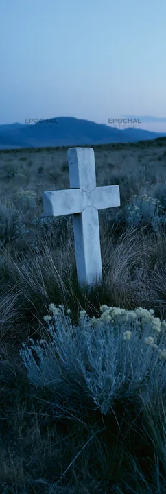 White Christian cross in remote meadow at dusk - AI-generated stock image