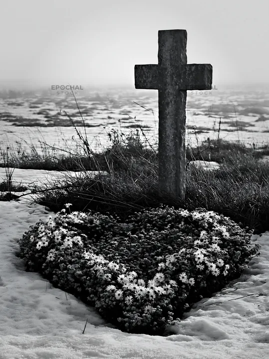 Stone Christian cross in snowy meadow with flowers - AI-generated stock image