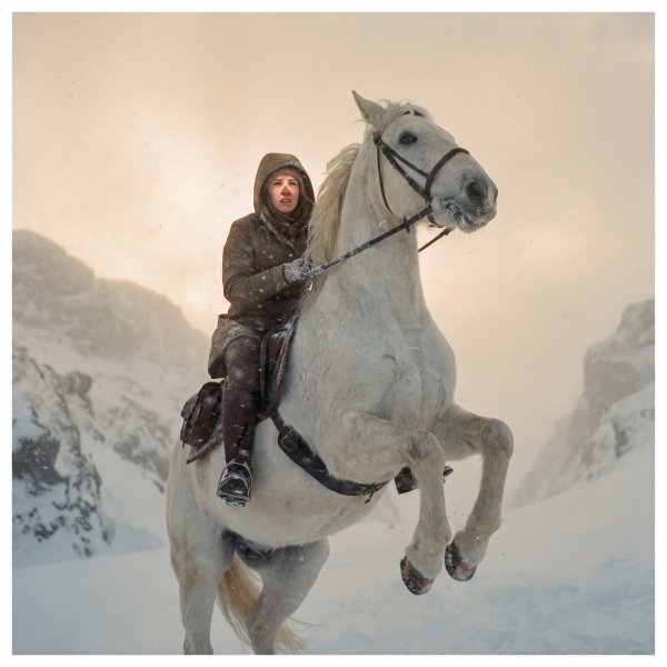 Rider on a white horse in snow-covered mountains during winter - stock photo