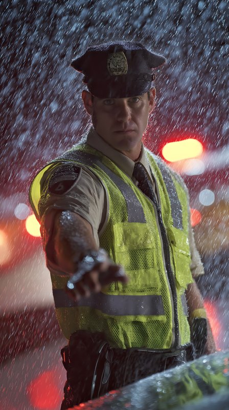 Rain falls as a police officer directs traffic at night Free Premium Stock Image - stock photo