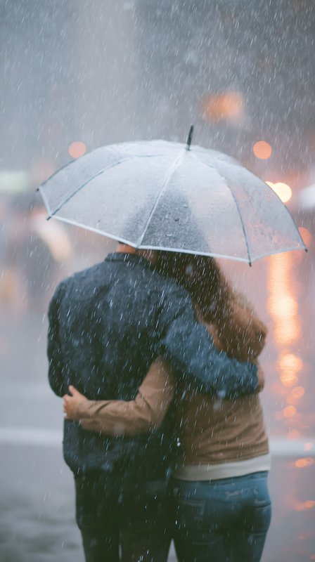 Couple shares an umbrella during a rain shower in the city Free Premium Stock Photo - stock photo