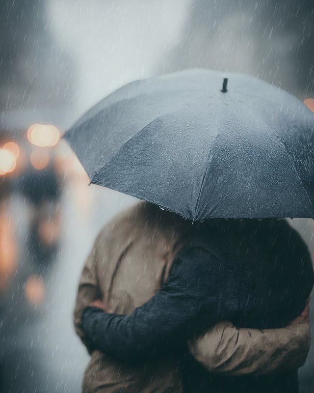 Couple shares an umbrella while hugging in the rain Free Premium Stock Photo - stock photo