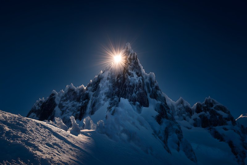 Snowy mountain peak shines under the sun in the evening sky Free Premium Stock Image - stock photo