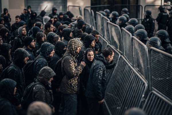 Crowd faces police barrier during protest in a city at night - stock photo