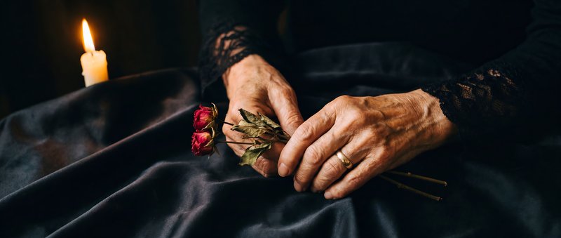 Hands holding dried roses near a lit candle at night Premium Stock Photo - stock photo