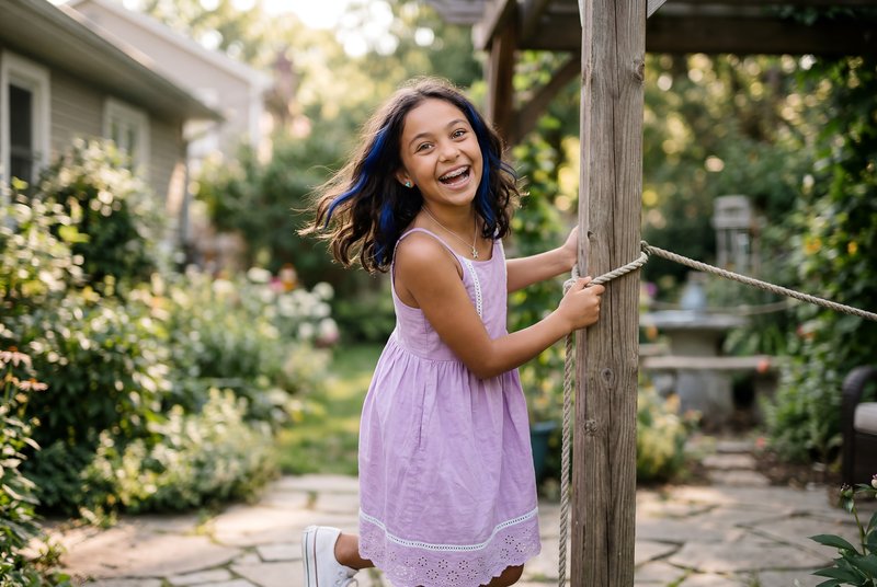 Girl plays on garden swing in sunny backyard in summer Premium Stock Image - stock photo