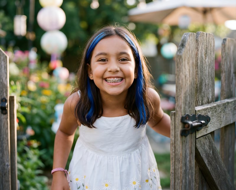 Girl smiles while standing at the garden gate in summer Premium Stock Image - stock photo