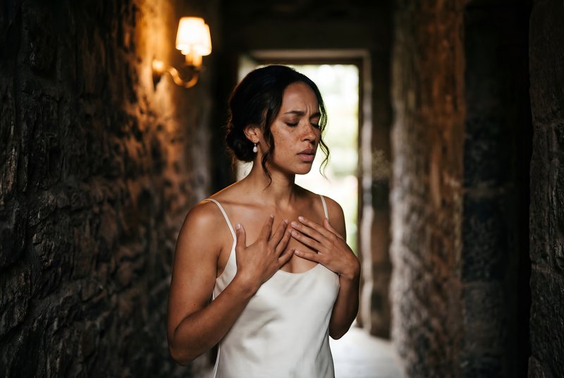 Woman stands in a hallway with closed eyes and hands on heart Premium Stock Photo - stock photo