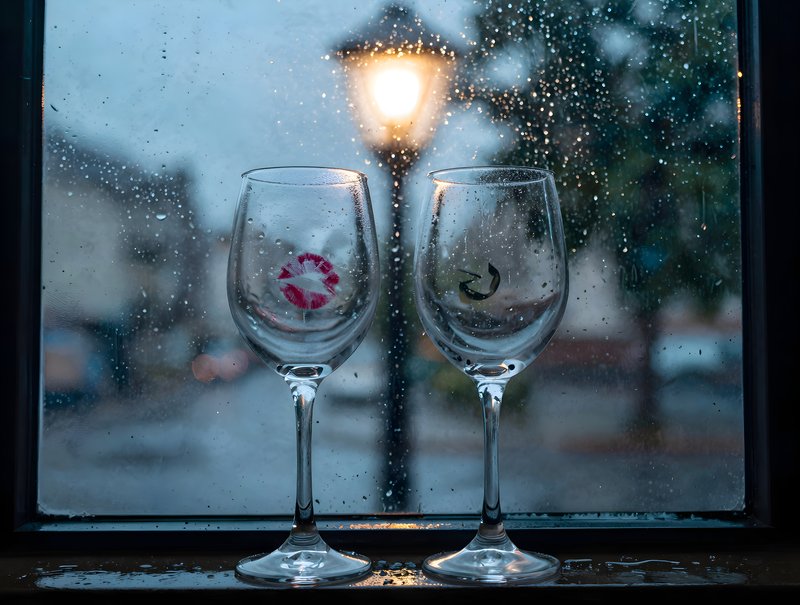Two wine glasses near a window on a rainy evening Premium Stock Image - stock photo