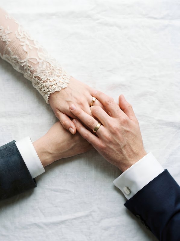 Couple holds hands while displaying wedding rings indoors Premium Stock Photo - stock photo