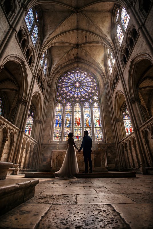 Couple stands hand in hand in a historic cathedral at dusk Premium Stock Photo - stock photo