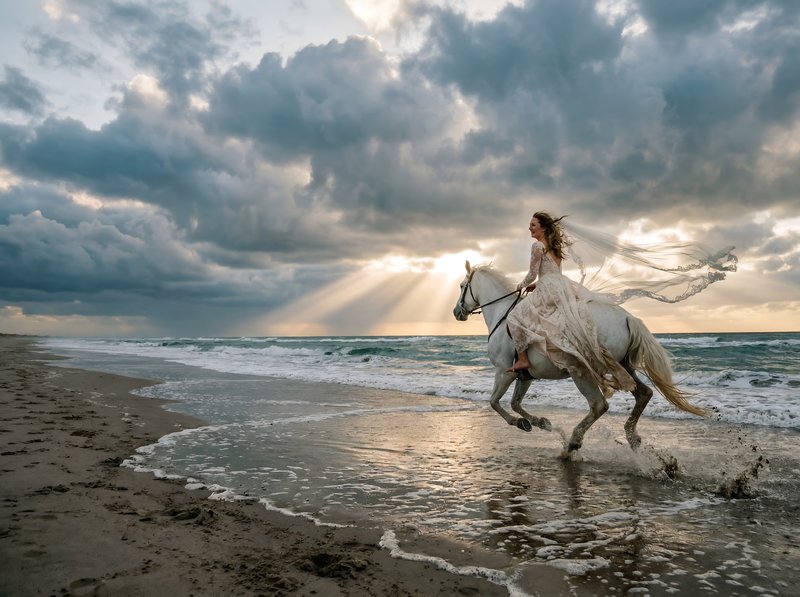 Woman rides horse on beach at sunset near ocean waves Premium Stock Image - stock photo