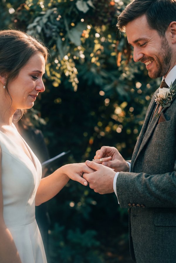 Couple exchanges wedding rings in garden during ceremony in autumn - stock photo