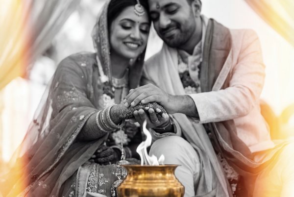 Couple performs ritual during wedding ceremony in outdoor setting - stock photo