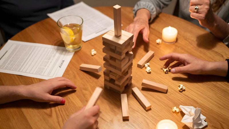 Friends play a stacking game with wooden blocks in a home setting Premium Stock Image - stock photo