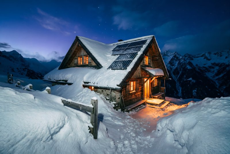 Snowy mountain cabin at night with lights glowing Premium Stock Image - stock photo