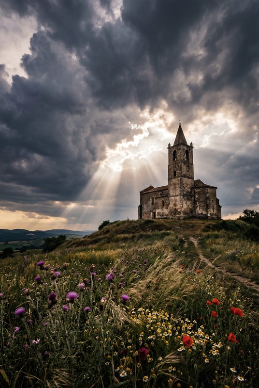 Cloudy sky shines over old church on a hillside Premium Stock Photo - stock photo