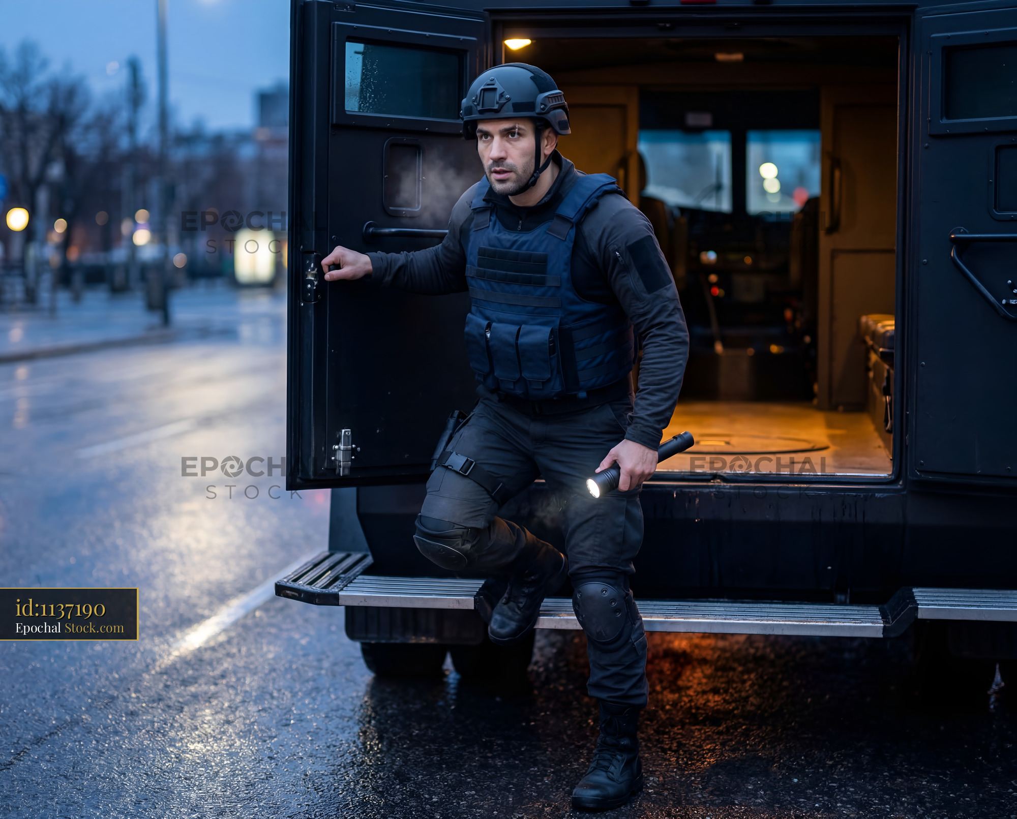 Officer steps out of armored vehicle while on duty at night Premium Stock Image