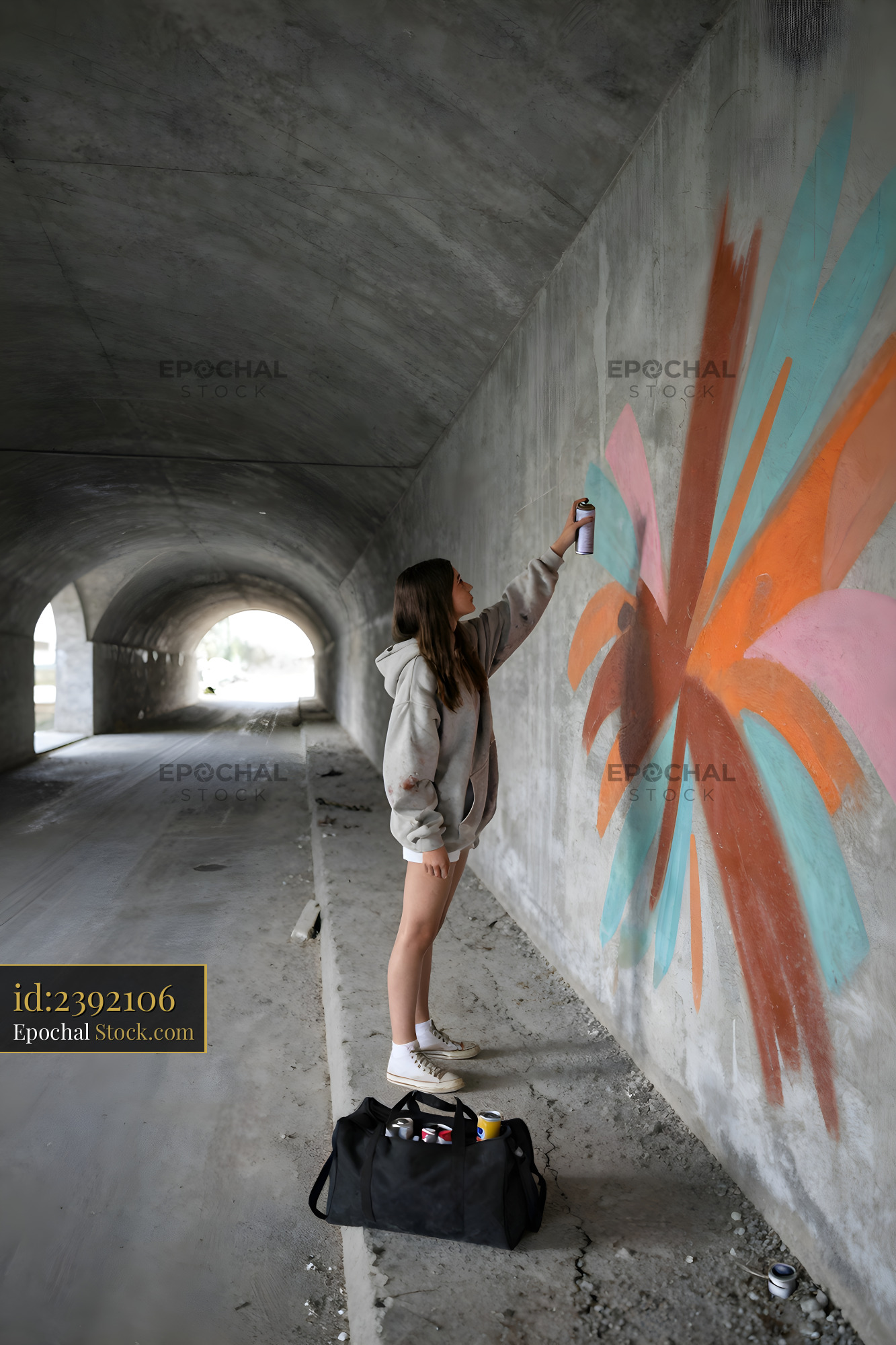 Spray painting bright design in tunnel during the day Premium Stock Image